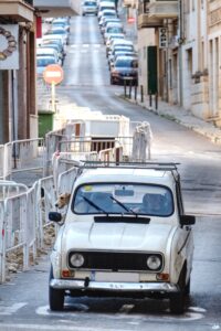 white car driving up a French street